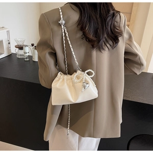 Détail du sac nuage plissé crème avec nœud en perles et pendentif cœur argenté
