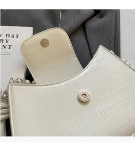 Detail of off-white wavy texture handbag with silver magnetic clasp and pearl chain