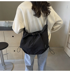 Detail view of the black nylon tote bag showing drawstring ruched design and shoulder strap