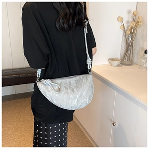 Rear view of a model wearing the metallic crinkled crescent crossbody bag in silver