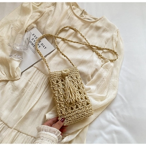 Detail of beige hand-woven crochet phone bag featuring hollow pattern and fringe tassels