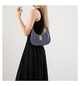 Détail du sac hobo bleu à motif crocodile avec boucle en métal doré porté à l'épaule
