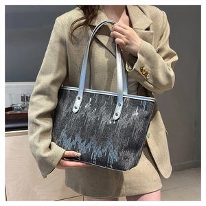 Detail of grey sequin tote bag with metallic sheen and silver faux leather handles