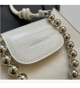 Detail of white textured leather bag with silver chain and Fashion & YM embossed logo