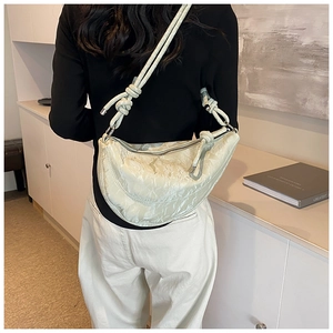 Detail of cream crescent bag with pleated texture and stylish knotted shoulder strap