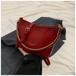 Detail of red glossy leather bucket bag with chunky gold chain strap and logo
