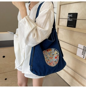 Close-up of a blue denim tote bag featuring a vibrant dragon embroidery patch