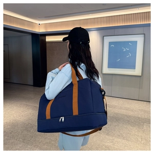 Détail du sac de voyage bleu avec sangles orange montrant le compartiment inférieur