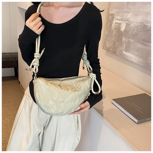 Detail of light green crescent bag featuring pleated texture and unique knotted strap design
