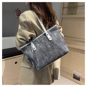 Detail of silver sequin tote bag showing sparkling vertical textures and leather straps