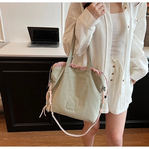 Detail of sage green canvas tote with pink drawstring closure and woven shoulder strap