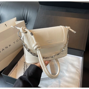Detail of creamy white bucket bag with glossy leather texture and silver chain