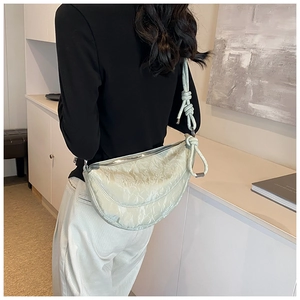 Detail of light green pleated croissant bag with thick decorative knotted shoulder strap