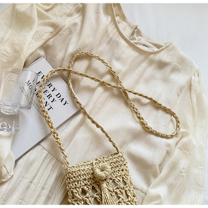 Detailed close-up of woven mini crossbody bag with long tassels and bohemian design