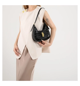 Détail d'un sac sous les aisselles à motif crocodile noir avec boucle en métal doré élégante