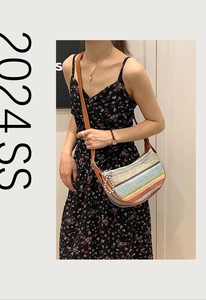 Detail of colorful striped woven shoulder bag with pearl pendant and brown leather strap