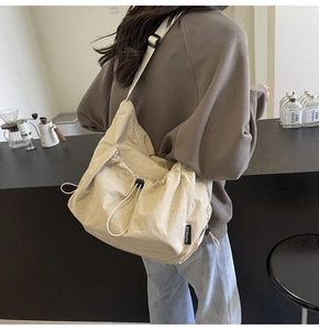 Detail of beige nylon tote bag with drawstring closure and adjustable shoulder strap