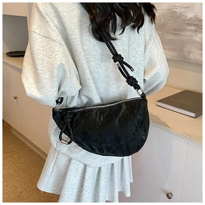 Detail of black pleated croissant bag with knotted strap and silver hardware accents