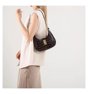 Sac sous le bras tendance marron foncé motif crocodile porté avec tenue élégante