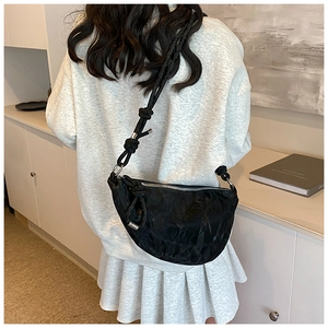 Close-up of black crescent dumpling bag featuring pleated cloud texture and knotted strap