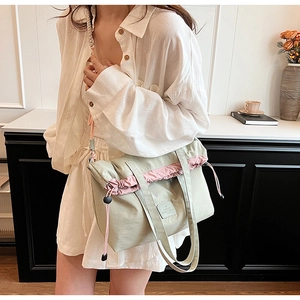 Detail of mint green canvas tote with dusty pink drawstring and Famtile logo label