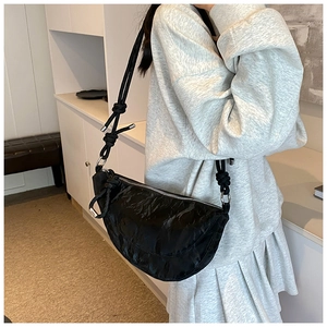 Detail of black crinkled crescent bag featuring a unique knotted shoulder strap and silver hardware