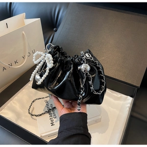 Détails du sac seau en cuir verni noir avec nœud en perles et chaîne argentée