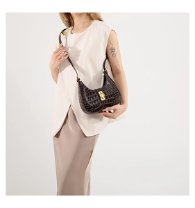 Détail du sac à bandoulière marron foncé en cuir de crocodile avec boucle dorée