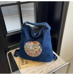 Detailed close-up of dragon embroidery on a premium dark blue denim tote bag
