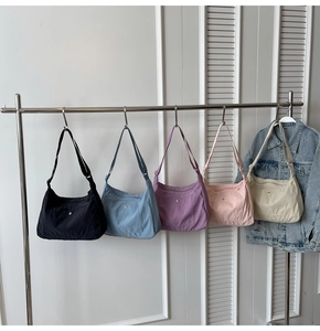 Detailed display of crescent nylon crossbody bags in five colors on a clothing rack