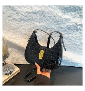Détail du sac bandoulière noir motif crocodile avec un fermoir doré carré poli brillant