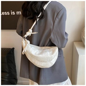 Detail of white pleated dumpling bag featuring a thick knotted rope shoulder strap and metal rings
