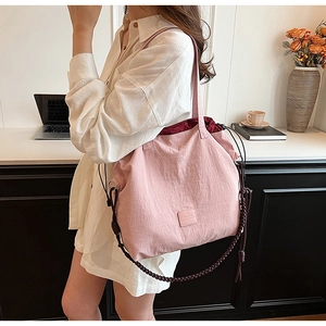 Detail of light pink canvas tote bag featuring burgundy drawstring closure and leather logo