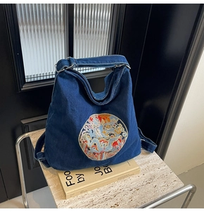 Close-up of a blue denim tote bag featuring intricate colorful dragon embroidery