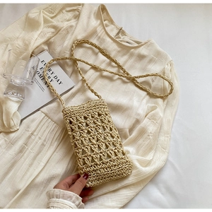 Close-up of lightweight woven straw phone bag with intricate openwork on a summer dress