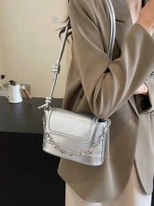 Chic silver metallic bucket bag with chain detail and knotted strap on khaki blazer