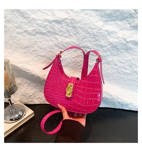 Détail du sac porté épaule fuchsia motif crocodile avec fermoir rotatif doré