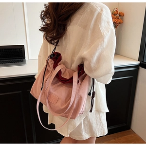 Detailed view of pink nylon drawstring shoulder bag with dual handles and logo patch