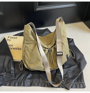 Close-up of olive green nylon tote bag featuring adjustable strap and drawstring detail