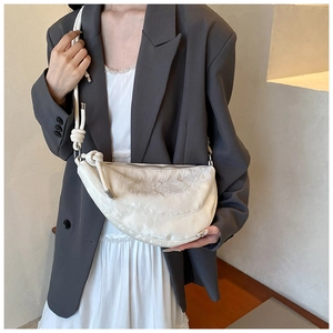 Detail of white half-moon crossbody bag featuring shiny texture and rope shoulder strap