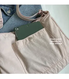 Detail view of pink nylon crossbody bag front pocket fitting a large tablet