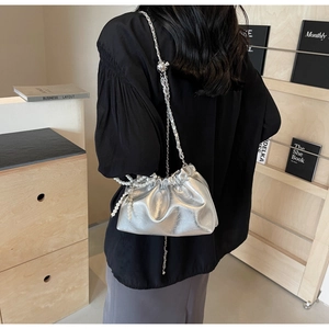 Sac seau argenté métallisé avec bandoulière chaîne et perle porté par modèle