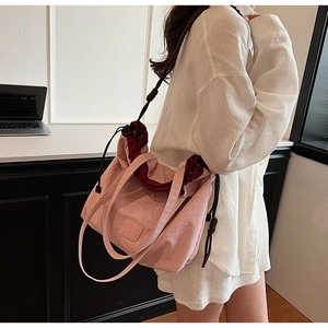 Pink canvas tote bag shown as a crossbody bag with dark red lining in a daily office scene