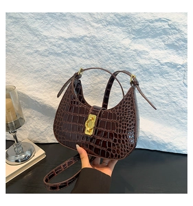 Détail du sac à bandoulière marron foncé motif crocodile avec fermoir rotatif doré