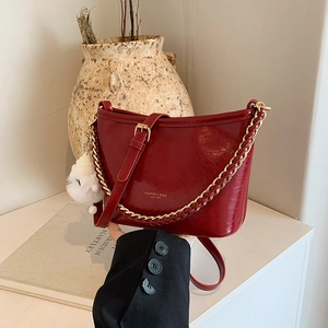 Fashionable dark red leather underarm bag with gold chain and plush charm pendant