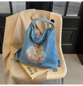 Detail of blue denim tote bag with exquisite dragon embroidery on white designer chair