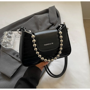 Detail of black crocodile texture handbag featuring silver bead strap and branding