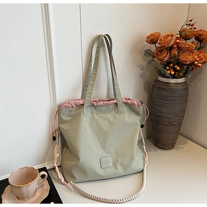 Close-up of lightweight green tote bag with pink drawstring and woven strap detail