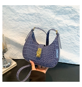Détail du sac violet avec gaufrage crocodile et fermoir en métal doré élégant