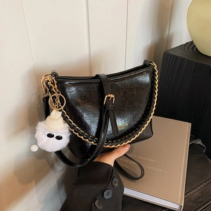 Chic black oil wax leather underarm bag with gold chain and plush monster charm